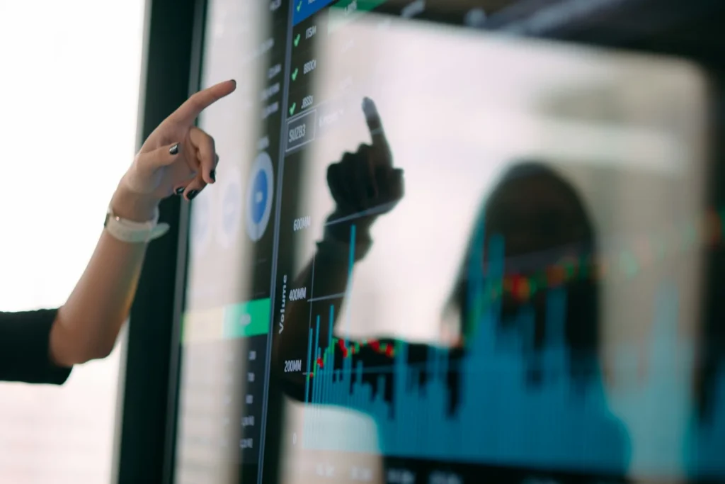 Deux personnes analysant des graphiques de performance sur un écran en réunion