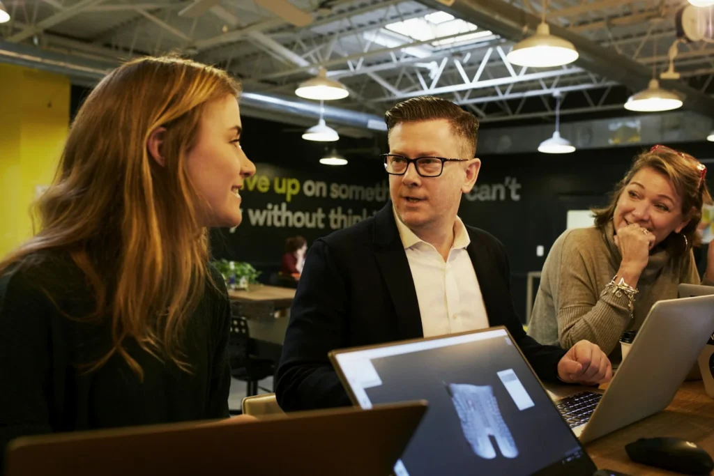 Équipe commerciale réunie autour d'ordinateurs portables dans un bureau