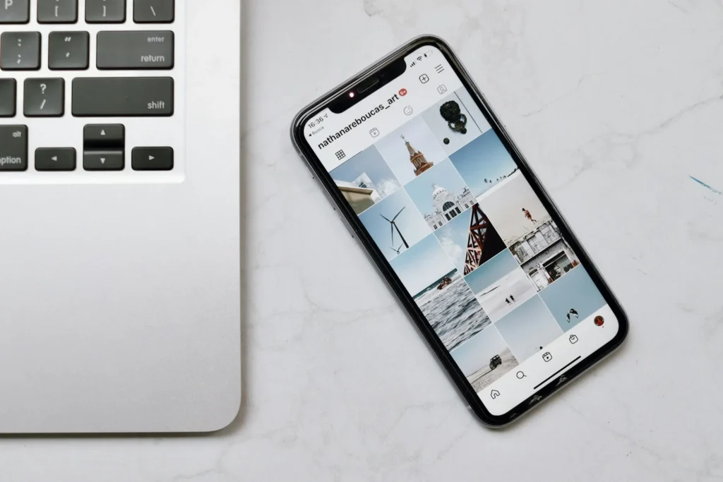Profil Instagram affiché sur un smartphone posé à côté d'un ordinateur portable