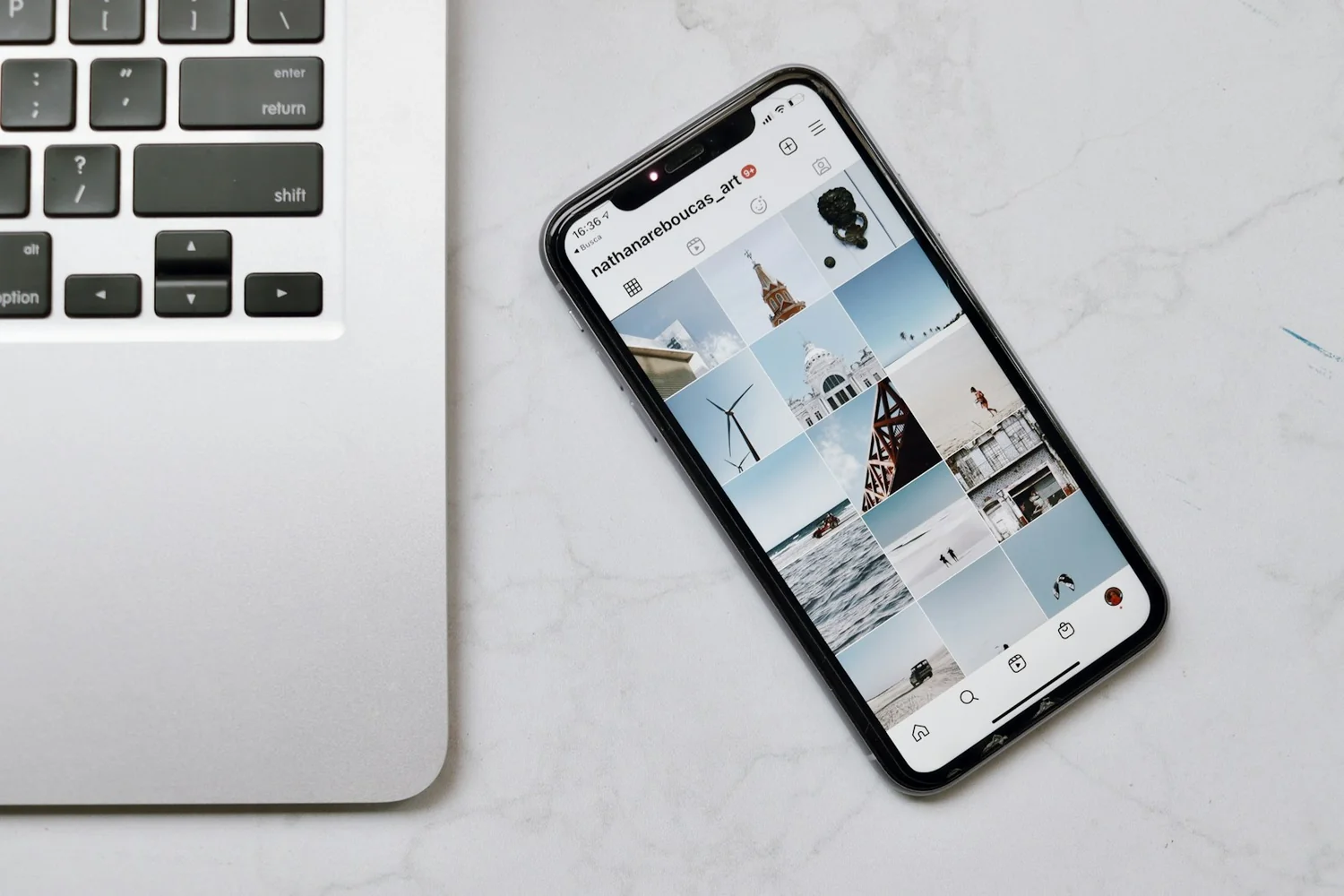 Profil Instagram affiché sur un smartphone posé à côté d'un ordinateur portable