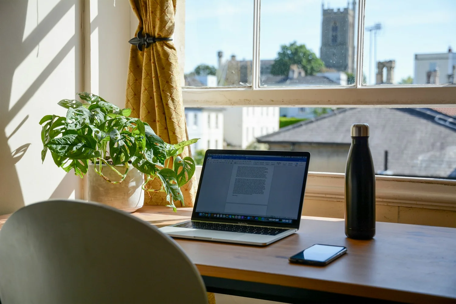 Bureau d'un indépendant avec un ordinateur portable devant une fenêtre