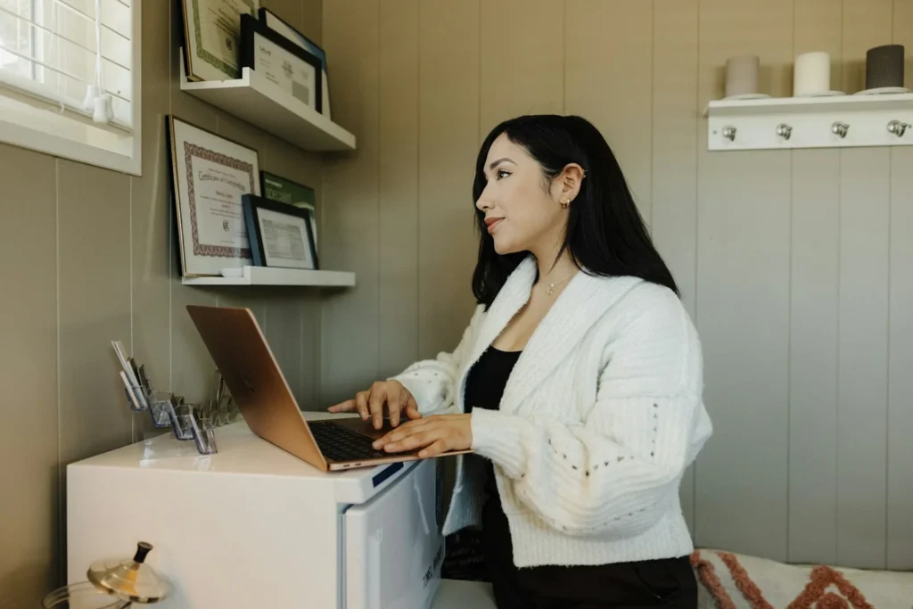 Une indépendante travaille sur son ordinateur portable dans son atelier, pour gérer son compte pro et sa comptabilité