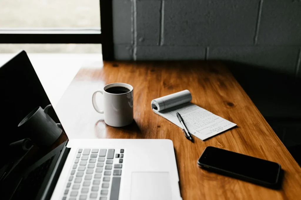 Ordinateur portable, tasse de café et bloc-notes sur un bureau en bois